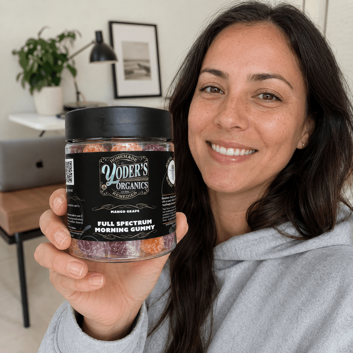 Smiling woman holding a jar of full spectrum CBG morning gummies